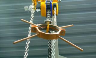 A rigging system in a warehouse with a rig attachment is connected to a chain hoist that supports the weight of a heavy object.