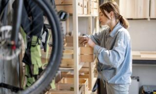 A young woman is looking through some neatly organized wooden crates in her clean and decluttered garage.