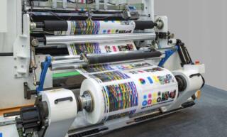 An industrial printer printing a ream of different color palettes in various formats onto a long roll of glossy paper.