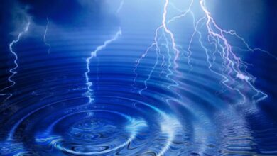 A water ripple emanating out in concentric circles with a bright lightning flash striking from clouds above it.