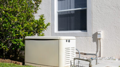 A rectangular standby generator installed in a backyard with a fuel pipeline connected to the house.
