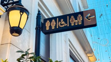 A directional sign on a pole next to a lamp indicates where restrooms and accessibility features are located.