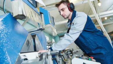 A manufacturing professional wearing safety gear as he moves a piece of PVC through a piece of machinery.