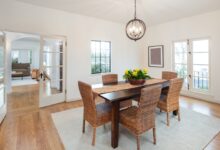 A simple family dining room with a rustic farmhouse table and six rattan wrapped chairs. There's a floral centerpiece.