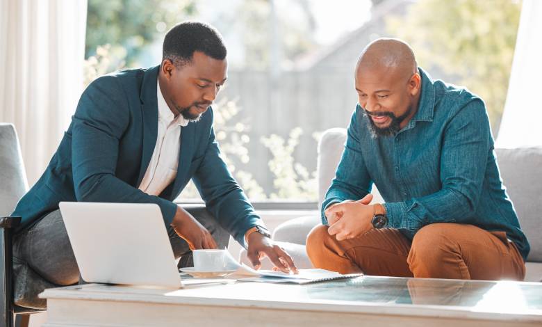 A broker is explaining a contract while speaking with a man in his house, possibly for a meeting to seek advice.
