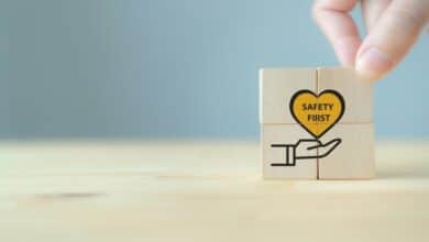 Close-up of a hand putting together wooden blocks that feature a heart with the words "Safety First" inside it.