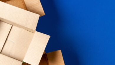 An overhead view of three cardboard boxes with the flaps spread open stacked in a pyramid against a royal blue background.