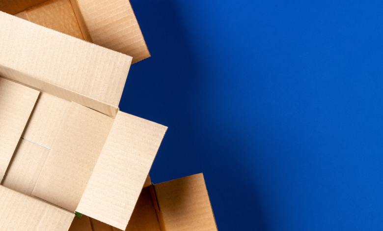 An overhead view of three cardboard boxes with the flaps spread open stacked in a pyramid against a royal blue background.