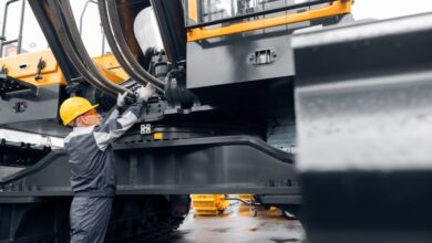 A professional mechanic is inspecting heavy-duty equipment on an excavator to aid in progressing the work.