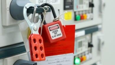 A close-up of a section of industrial electrical equipment. A red padlock attached to a handle reads "Danger: Locked Out."