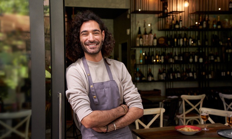 A happy young adult local small-business owner looking into the camera with his arms crossed, showing a positive attitude.