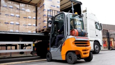 A forklift is lifting and unloading items from a semi-truck at a company's shipping docking station.
