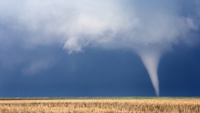 A small tornado cutting through some farm fields. The crops have already been harvested from this area.