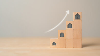 10 wooden blocks arranged as a staircase, the outer four with images of buildings on them. A nearby digital arrow sweeps upward.