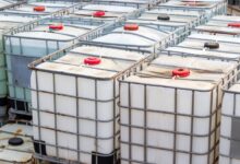 Rows of intermediate bulk containers (IBCs) stacked on top of each other. Metal cage covers each of the containers.